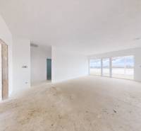 Prostorný, světlý interiér rodinného domu s velkými okny a neutrálními stěnami.