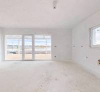 Interiér rodinného domu s velkými okny a výhledem na zahradu.