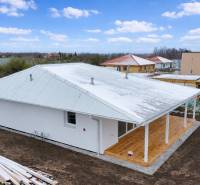 Rodinný dům v Novém Světě s bílou fasádou a terasou s dřevěným dekorem.