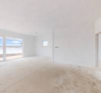 Světlá místnost v rodinném domě s okny a podlahou s dřevěným dekorem.