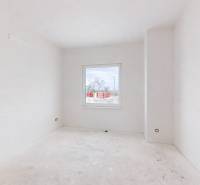 Prázdná místnost na staveništi v rodinném domě s bílými stěnami a oknem.