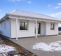 Rodinný dům v Novém Světě se sněhovými náznaky na zahradě a dlážděným chodníkem.