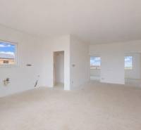 Prostorná bílá místnost v rodinném domě bez nábytku, s výhledem na okolí.