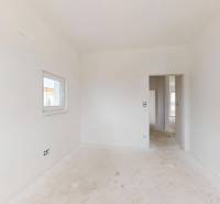 Prázdný bílý interiér v rodinném domě s oknem a dveřmi bez podlahy s dřevěným dekorem.