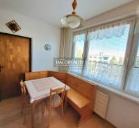 Jídelna ve 3-pokojovém bytě s podlahou s dřevěným dekorem a velkými okny.