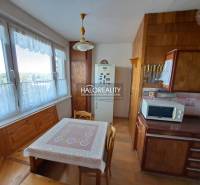 Obývací pokoj v 3-pokojovém bytě s podlahou s dřevěným dekorem, sedací souprava a nástěnné dekorace.