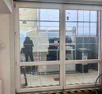 Skleněné posuvné dveře v obchodních prostorách, kolo, radiátor a plastová fólie na stěně.