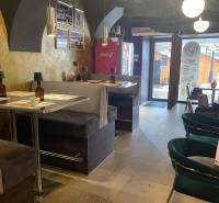 Interiér gastro prostoru s pohodlnými sedadly a dekorativními svítidly.