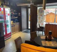 Interiér gastro prostor s kruhovým stolem, židlemi a osvětlením.