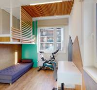 Dětský pokoj s postelí, psacím stolem, kobercem, podlahou s dřevěným dekorem a kolem.