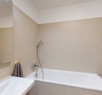 Koupelna s vanou a béžovými obklady ve 4pokojovém bytě.