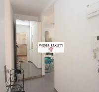 Chodba v 2-pokojovém bytě s věšákem, zrcadlem a dlažbou.