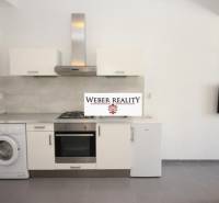 Kuchyně v 2-pokojovém bytě se spotřebiči a televizorem na stěně.