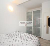 Ložnice s manželskou postelí, vestavěná skříň, bílé stěny ve 2pokojovém bytě.