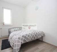 Ložnice v dvoupokojovém bytě s postelí a podlahou s dřevěným dekorem.