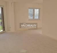 Interiér rodinného domu s velkým oknem, bílými stěnami a terasovými dveřmi.