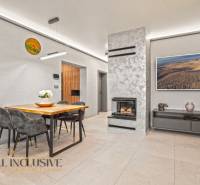 Obývací pokoj v rodinném domě s krbem, stolem pro čtyři a dekoracemi.