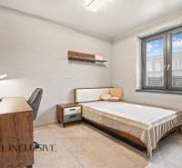 Ložnice v rodinném domě s jednoduchým zařízením, psacím stolem a pohodlnou postelí.