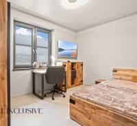 Dětský pokoj v rodinném domě s pracovním stolem, postelí a podlahou s dřevěným dekorem.