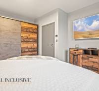 Ložnice v rodinném domě s nábytkem a skříní s dekorem přírodního dřeva.