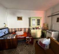 Pokoj s gaučem, kuchyňskou linkou, sporákem a televizí v rodinném domě.