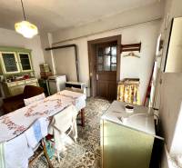 Jídelna v rodinném domě s kamny, stolem a starým nábytkem.