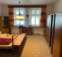 Ložnice v rodinném domě s kobercovou podlahou a nábytkem ve světlých barvách.