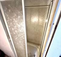 Sprchový kout v interiéru rodinného domu s obkladem a dekorativní podlahou.