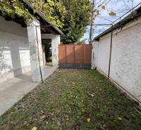 Dvůr rodinného domu v Jablonci s kamennou dlažbou a zelení.