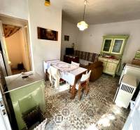 Interiér rodinného domu s keramickou podlahou, kuchyňskou linkou a jídelním stolem.