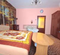 Ložnice v rodinném domě s tapetou lesa a klasickým dřevěným nábytkem.