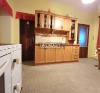 Kuchyně v rodinném domě s dřevěnými skříňkami a klasickým sporákem.