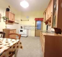 Kuchyně v rodinném domě s jídelním stolem a dřevěnými skříňkami.