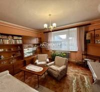 Obývací pokoj rodinného domu s nábytkem s dřevěným dekorem a záclonami.