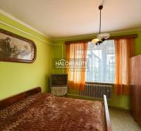 Ložnice v rodinném domě s postelí, obrazem, skříňkou a televizí.