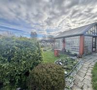 Zahrady ve Spišské Nové Vsi se skleněným domem, upraveným trávníkem a květinovým záhonem.