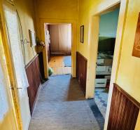 Chodba s kobercem a dřevěným obložením v rodinném domě, místnost vpravo.