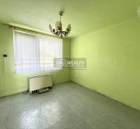 Pokoj s lustrem, oknem a topným tělesem v 3-pokojovém bytě.