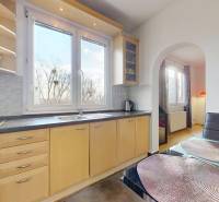 Kuchyně ve 3-pokojovém bytě s velkým oknem, světlým nábytkem a podlahou s dřevěným dekorem.