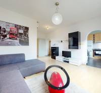 Obývací pokoj v 3-pokojovém bytě s pohovkou, obrazem a podlahou s dřevěným dekorem.