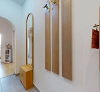 Chodba s dlažbou a věšákem vede do pokoje 3pokojového bytu.