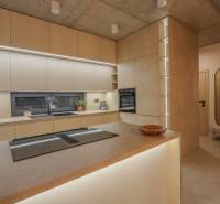 Kuchyně v rodinném domě se zabudovanými spotřebiči, pracovními deskami a podlahou s dřevěným dekorem.