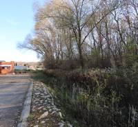 Stavba rodinného domu v Nitře na Drieňové ulici, obklopená přírodou a stromy.