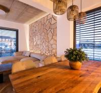 Interiér rodinného domu s kamennou stěnou, pohodlnou sedačkou a podlahou s dřevěným dekorem.