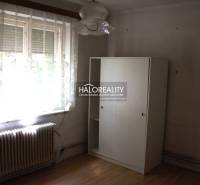 Pokoj v rodinném domě s velkým oknem, radiátorem a bílou skříní.