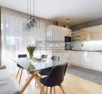 Kuchyně v rodinném domě s jídelním stolem, sedačkou a podlahou s dřevěným dekorem.