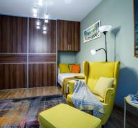 Pokoj s pohodlným křeslem, šatní skříní, lustrem a podlahou s dřevěným dekorem v rodinném domě.