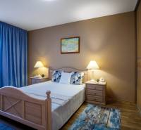 Ložnice v rodinném domě s postelí, nočními stolky a podlahou s dřevěným dekorem.