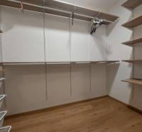 Šatník v 2-pokojovém bytě s poličkami a podlahou s dřevěným dekorem.