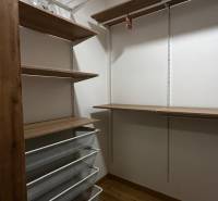 Úložné prostory s drátěnými koši a poličkami v 2-pokojovém bytě, podlaha s dřevěným dekorem.